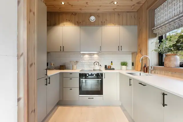 Kjøkkenet fra Sigdal har et moderne og stilfullt design med gode benkeflater og rikelig med oppbevaringsplass. Innredningen har lysegrå, glatte fronter og hvit laminatbenkeplate med underlimt oppvaskkum.