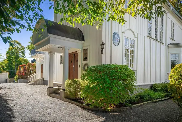 Velkommen inn i en ærverdig og klassisk utformet villa. Her får man et unikt familiehjem med mye sjel og historie i veggene. Inngangen gir et godt førsteinntrykk, med buet yttertak, vakre søyler og tofløyet ytterdør i mørkt tre.