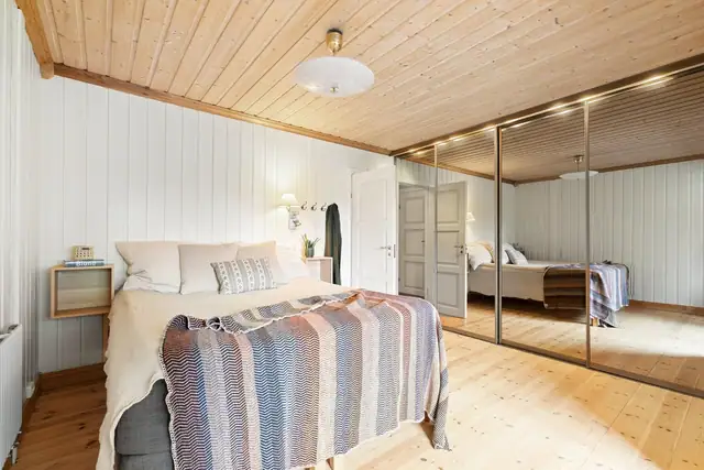 I tillegg har rommet skyvedørsgarderobe med speilfronter langs den ene veggen.