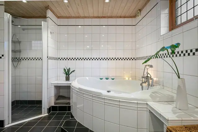 I det ene hjørnet av rommet er det et innfliset boblebad og i et annet hjørne en dusjnisje med glassdør.