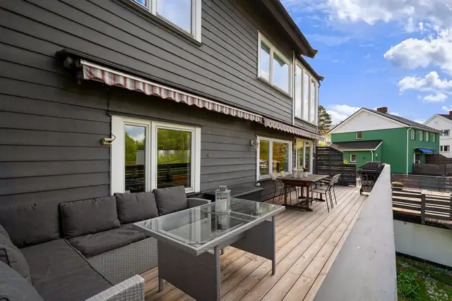 Terrassen utenfor stuen er nylig utbedret og har dekke av terrassebord, rekkverk i tre og skjermende, elektriske markiser.