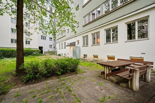 Bakgården er skjermet og opparbeidet med gressplen, beplantning og sittegrupper.