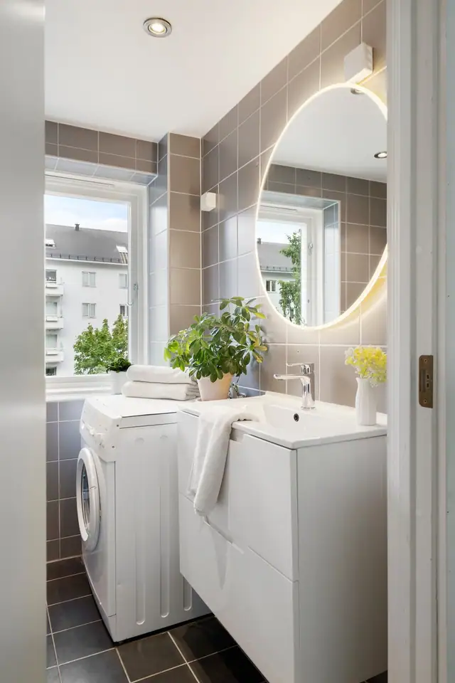 Lyst og flislagt baderom med varme i gulvet og downlights i himling. Opplegg for vaskemaskin.