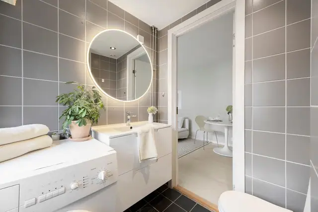 Badet har tidløse fliser og oppleves som svært innbydende og romslig. Opplegg for vaskemaskin.