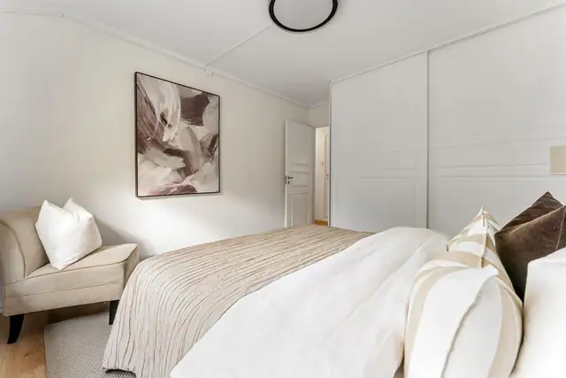 På hovedsoverommet er det god oppbevaring i en skyvedørsgarderobe med hvite, profilerte fronter.