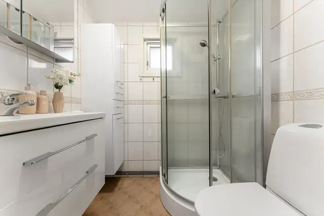 Badet i 2. etasje har lyse vegg- og gulvfliser, i tillegg til toalett, dusjkabinett og varmekabler.