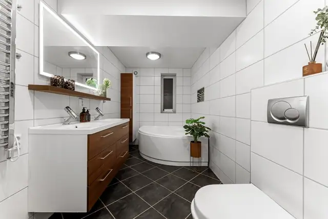 Boligen har bad både i 2. etasje og i underetasjen. Nede er badet innredet med sorte gulvfliser og store, hvite veggfliser.