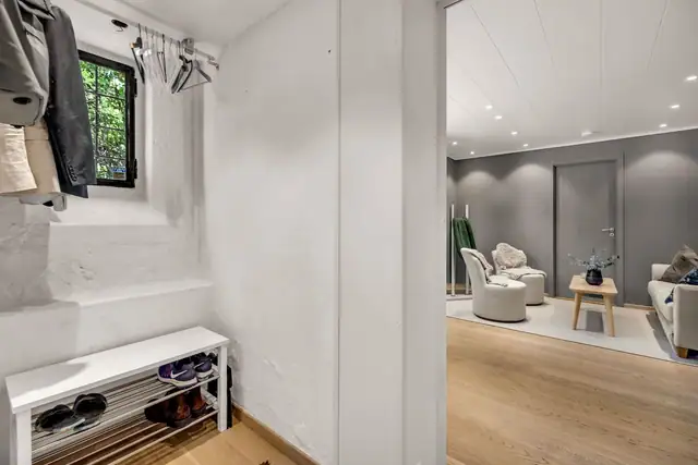 Vel inne blir vi ønsket velkommen i en pen entré med parkettgulv med vannbåren gulvvarme - en komfortdetalj som er gjennomgående for leilighetens oppholdsrom.