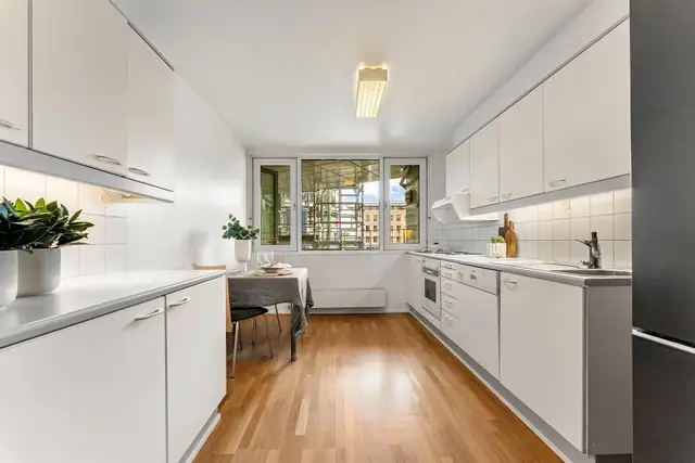 Kjøkkenet har et tidløst design med gode benkeflater og rikelig med oppbevaringsplass. Innredningen har hvite, glatte fronter og lysegrå laminatbenkeplate med nedfelt kum i stål.