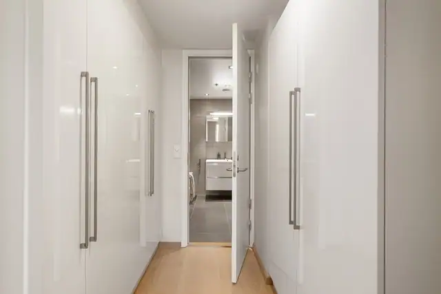 Hovedsoverommet har adkomst til badet via et walk-in closet med store, takhøye garderobeskap fra Crown med hvite høyglansfronter.