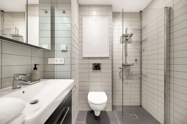 Innredningen består av heldekkende servant med sort skuffeseksjon og speilskap, som gir både et moderne uttrykk og praktisk oppbevaring. Badet er videre utstyrt med vegghengt toalett, opplegg for vaskemaskin og vannbåren gulvvarme. Balansert ventilasjon o